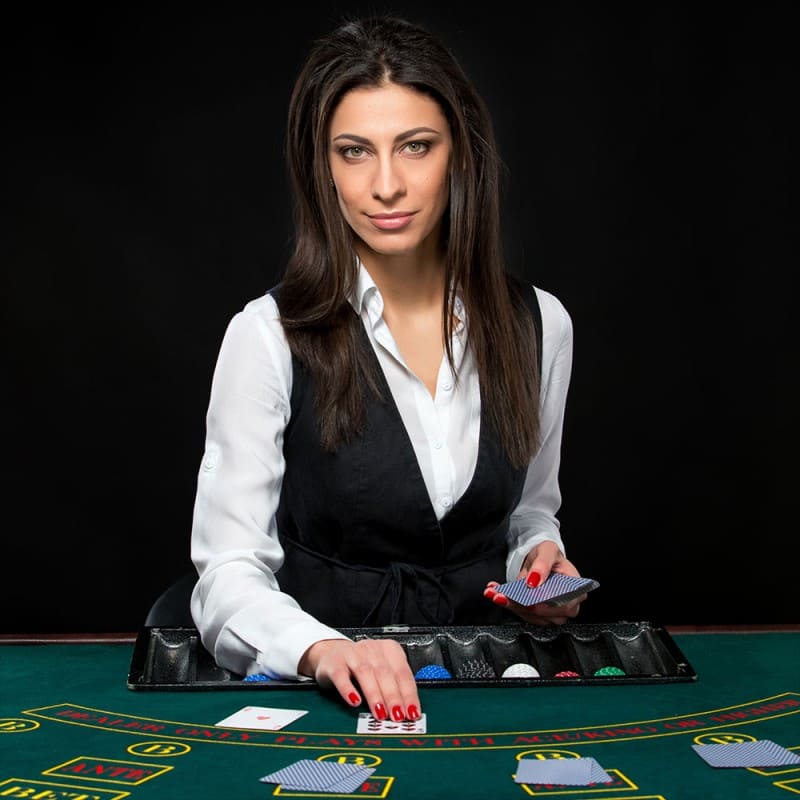 A courteous dealer engaging players at a live Baccarat table